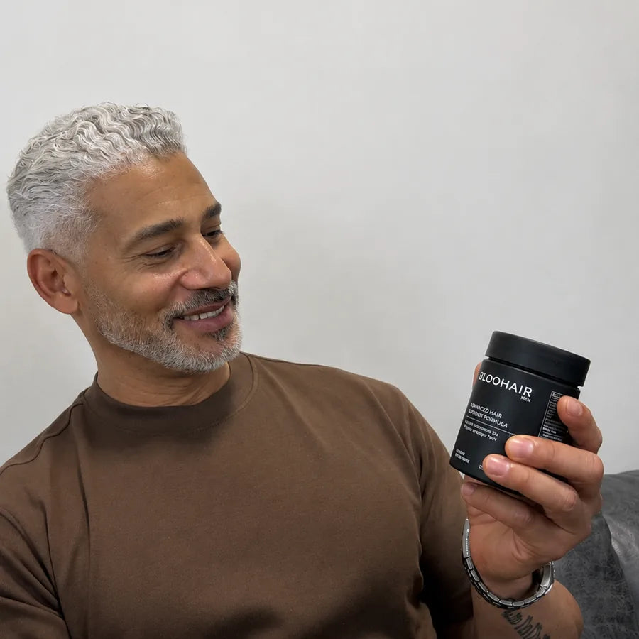 A silver-haired man holding a bottle of BLOOHAIR MEN — 120 capsules, four a day with a meal, 30 days per bottle